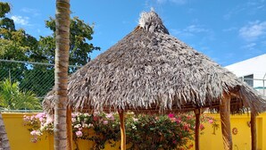 An outdoor patio with a thatched roof, a brick floor, and a table with chairs. - Amplia Casa Para Renta Vacacional en Mazatlán a Solo 6 Minutos de la Playa (Mazatlán)
