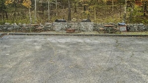 Un espace aménagé avec un revêtement de pavés, un muret en pierre, un banc en bois et un barbecue.