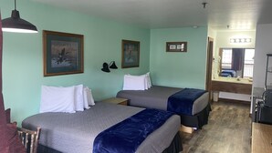 A hotel room with two beds, a desk, a chair, and a window with a view of the outside. - Double Queen Room w/Kitchen Supplies (Branson)