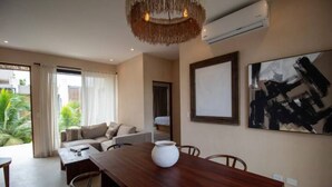Un salon moderne avec une table à manger en bois, un canapé et un grand tableau abstrait accroché au mur.