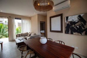 Ein modernes Wohnzimmer mit Esstisch aus Holz, einer Couch und einem großen abstrakten Gemälde an der Wand.
