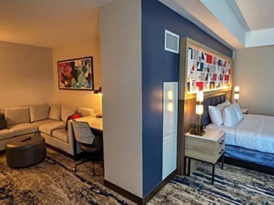 Ein Hotelzimmer mit Bett, Sofa, Schreibtisch und Nachttisch.