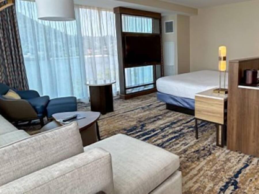 Quarto de hotel com cama, sofá, escrivaninha e cadeira.