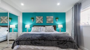 Un dormitorio con cama, dos mesitas de noche, un espejo y obras de arte en la pared.