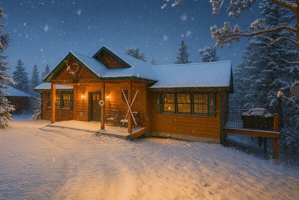 Uma cabana de madeira com telhado coberto de neve, um alpendre com esquis e uma paisagem nevada.