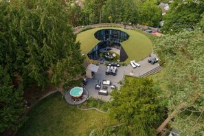 An aerial view of a modern house with a curved glass structure, a swimming pool, and a well-maintained lawn. - Hotel downtown Cancun with pool

 (Cancún)