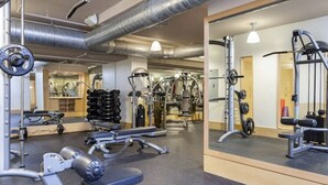 Une salle de sport équipée de divers appareils d’exercice, de miroirs et dotée d’un design moderne et épuré.