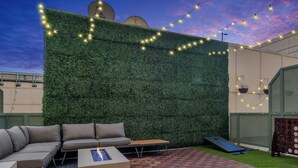 Une terrasse sur le toit agrémentée d’un mur végétal, de sièges extérieurs et d’une table de ping-pong.