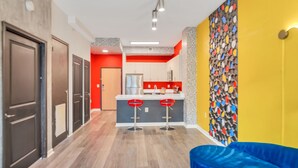 Une cuisine moderne aux touches de rouge, un coin bar avec des tabourets et une décoration murale colorée.