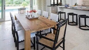 A modern kitchen with a large island, a dining area with a wooden table and chairs, and a view of the outdoors. - 2 Villas @ Windswept Residences (Frigate Bay)