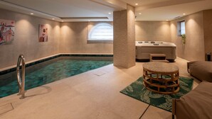 Un espace bien-être comprenant une piscine, un jacuzzi et une table de massage.
