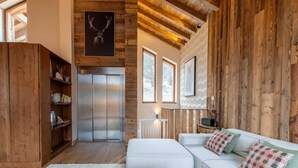 Un salon spacieux avec un canapé blanc, des étagères en bois, une cheminée et un plafond avec des poutres apparentes.