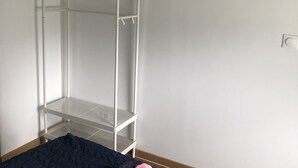 Une pièce avec un lit, une armoire en métal blanche et une prise de courant au mur.