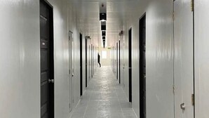 Een lange, smalle gang met deuren aan beide kanten, die uitkomt bij verschillende kamers.