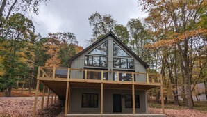 A two-story cabin with a balcony, surrounded by autumn foliage. - Clover House at Alpine Lake with pool access. (Terra Alta)