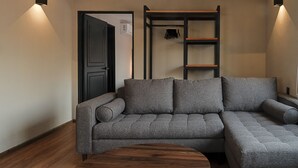 Ein modernes Wohnzimmer mit einem grauen Ecksofa, einem Holztisch und einer eingebauten Regaleinheit mit Kleiderstange.