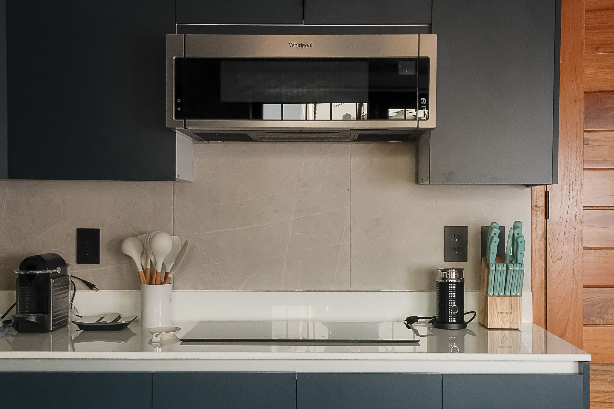 A modern kitchen with a stainless steel range hood, a coffee maker, and a knife block on the counter.