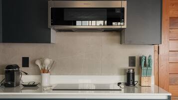 A modern kitchen with a stainless steel range hood, a coffee maker, and a knife block on the counter.
