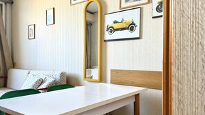 A room with a white table, green chairs, a wooden headboard, and framed pictures on the wall. - SE054 - Senigallia, sea-front studio at the Residence''Pyramids'' (Senigallia)