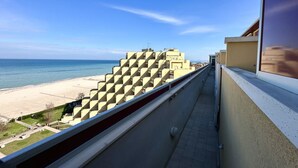 Un balcón con vista a la playa y un edificio de diseño geométrico singular.