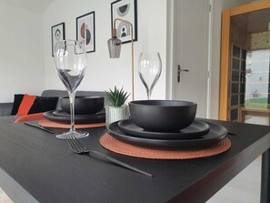 Mesa de jantar posta com tigelas pretas, um jarro de vidro para vinho e um garfo.