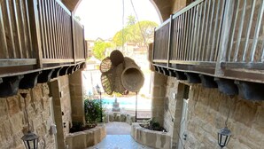 A stone-walled courtyard with a central pool, outdoor seating, and a staircase leading to an upper level.