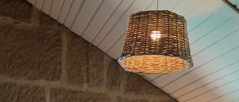 Une chambre avec un mur en pierre, un lit avec des oreillers, une lampe de chevet et des fenêtres.