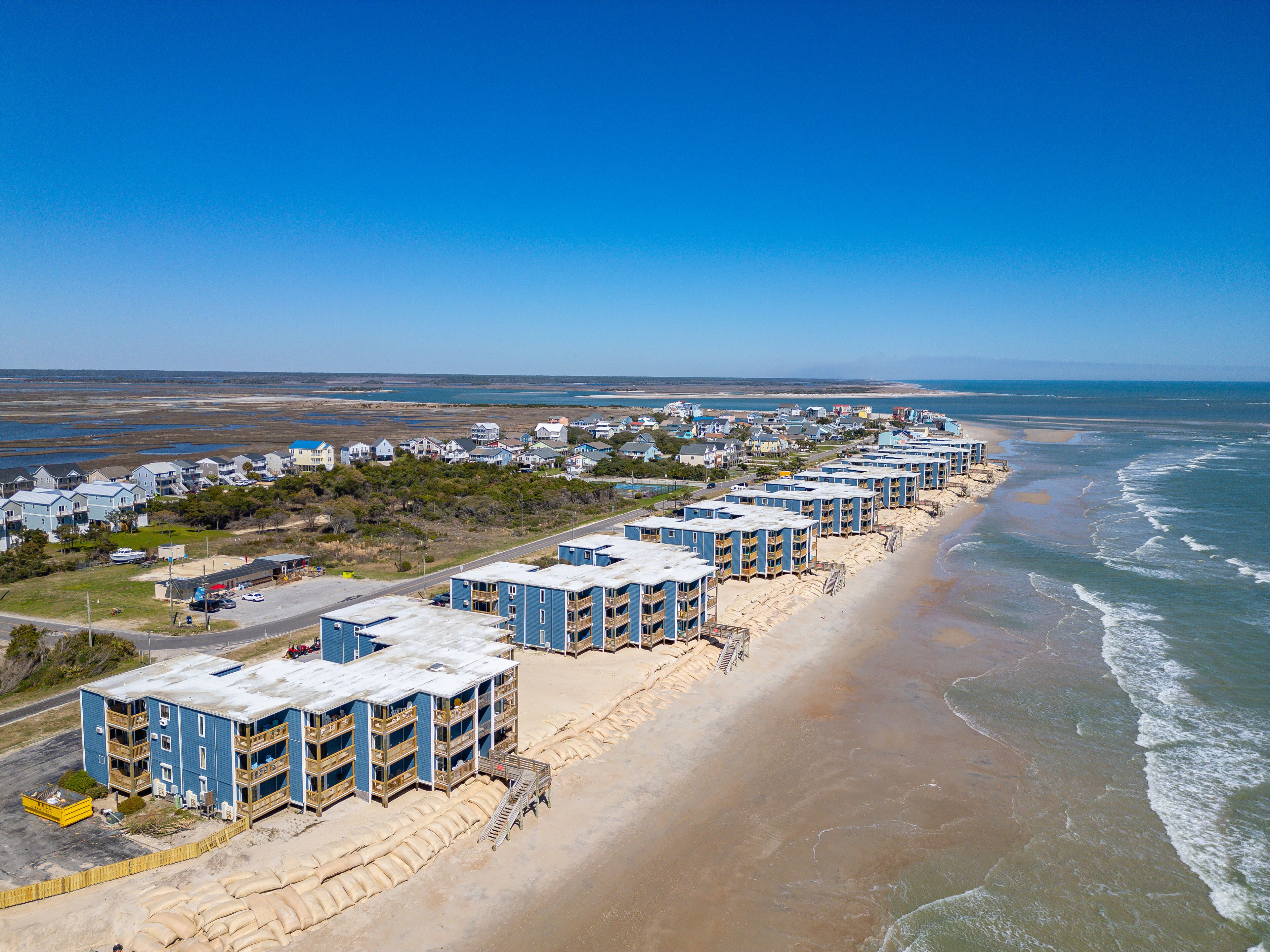 Een strandhotel met meerlaags gebouwen, een zandstrand en helder uitzicht op de oceaan.