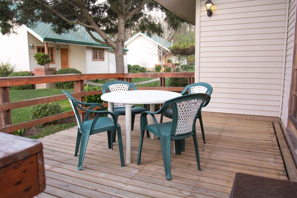 Una terraza de madera con una mesa redonda y cuatro sillas.