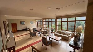 A spacious living room with a large window, a sofa, a coffee table, and a fireplace. - Hotel y Cabañas Huallilemu Sur- Caja Los Andes (El Quisco)