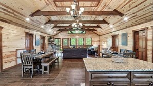 A spacious kitchen with wooden walls, a central island, and a dining area with benches and chairs.
