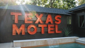 A sign for 'Texas Motel' with a pool area in front.