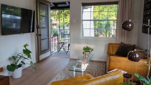 A living room with a sofa, a coffee table, a TV, and a window with a view of the outdoors.
