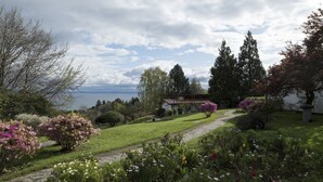 Um jardim com um caminho que leva a uma casa com vista para a água.