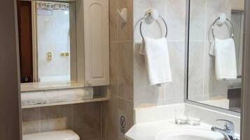 Un baño pequeño con inodoro, lavamanos y espejo.