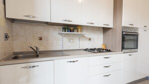 A modern kitchen with white cabinets, a stainless steel sink, a gas stove, and a built-in oven. - Mosse 82 apartment in Florence by Mmega (Firenze)