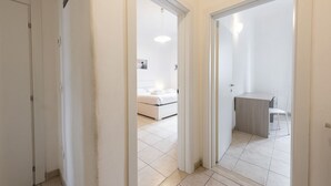 A hallway leading to a bedroom with a bed, a small table, and a chair. - Mosse 82 apartment in Florence by Mmega (Firenze)
