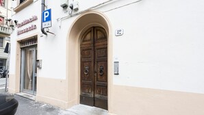 A building with a large wooden door, a blue parking sign, and a number '82' sign. - Mosse 82 apartment in Florence by Mmega (Firenze)