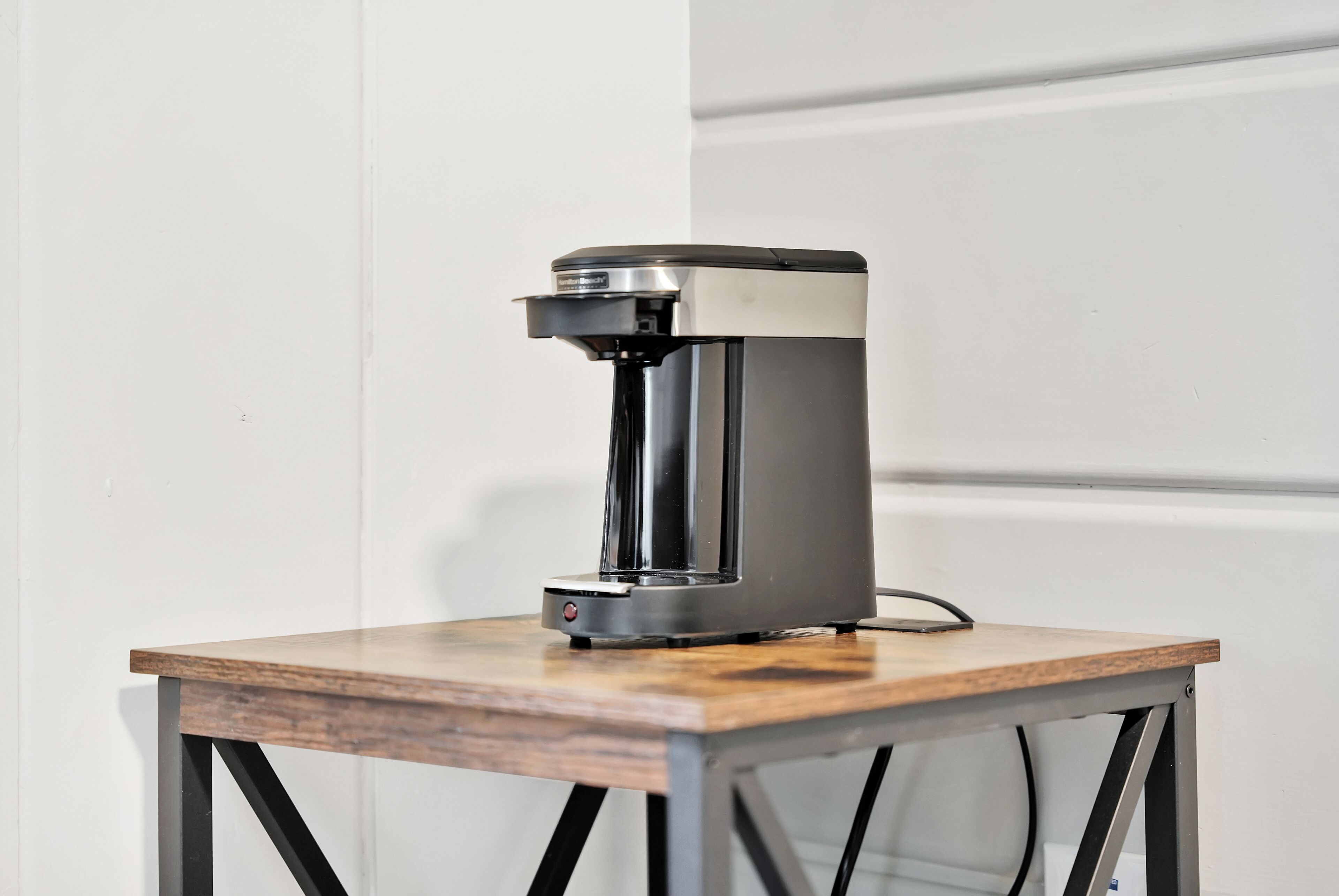 A coffee machine on a wooden table with metal legs.