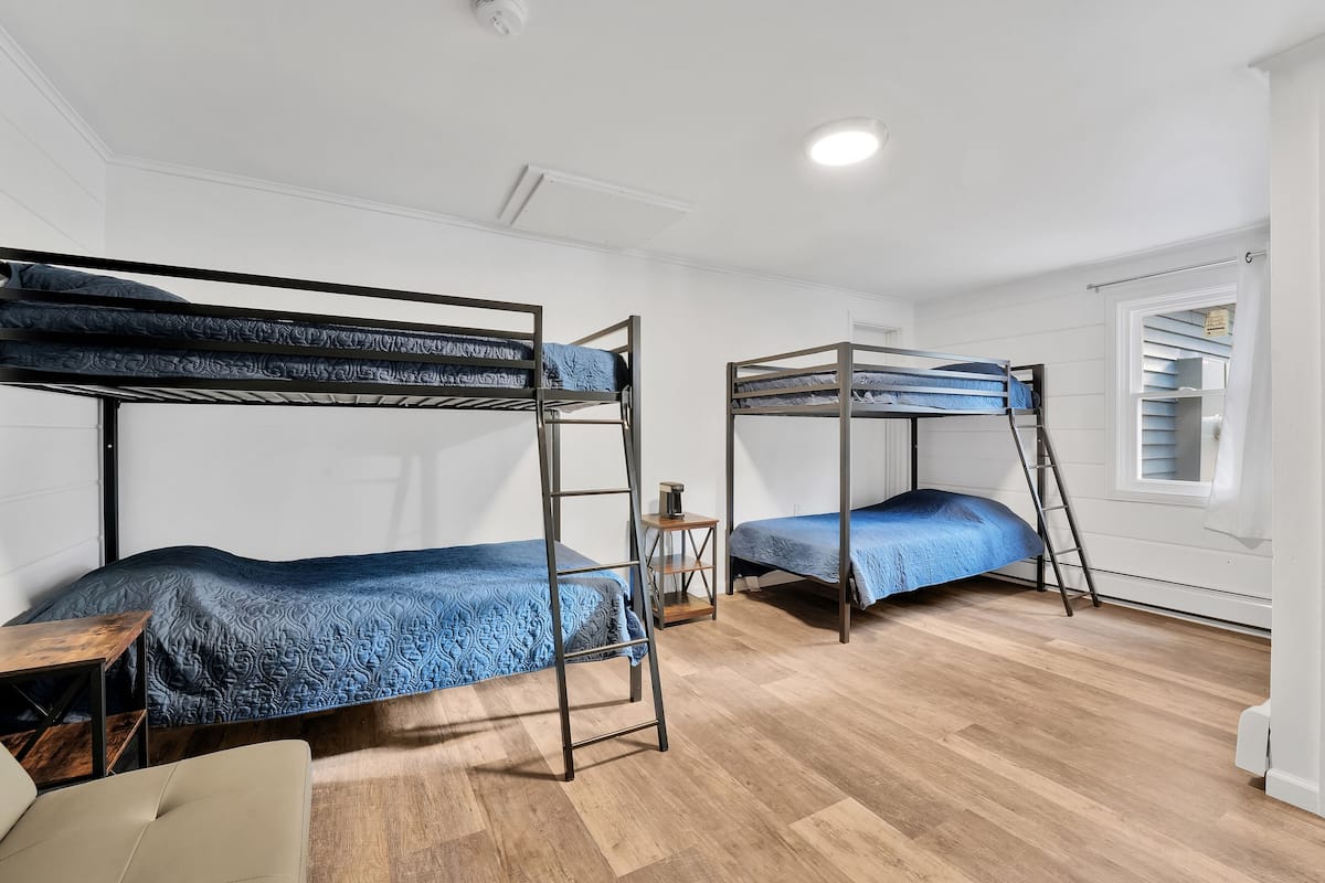 Una habitación con literas, un escritorio de madera y una escalera.
