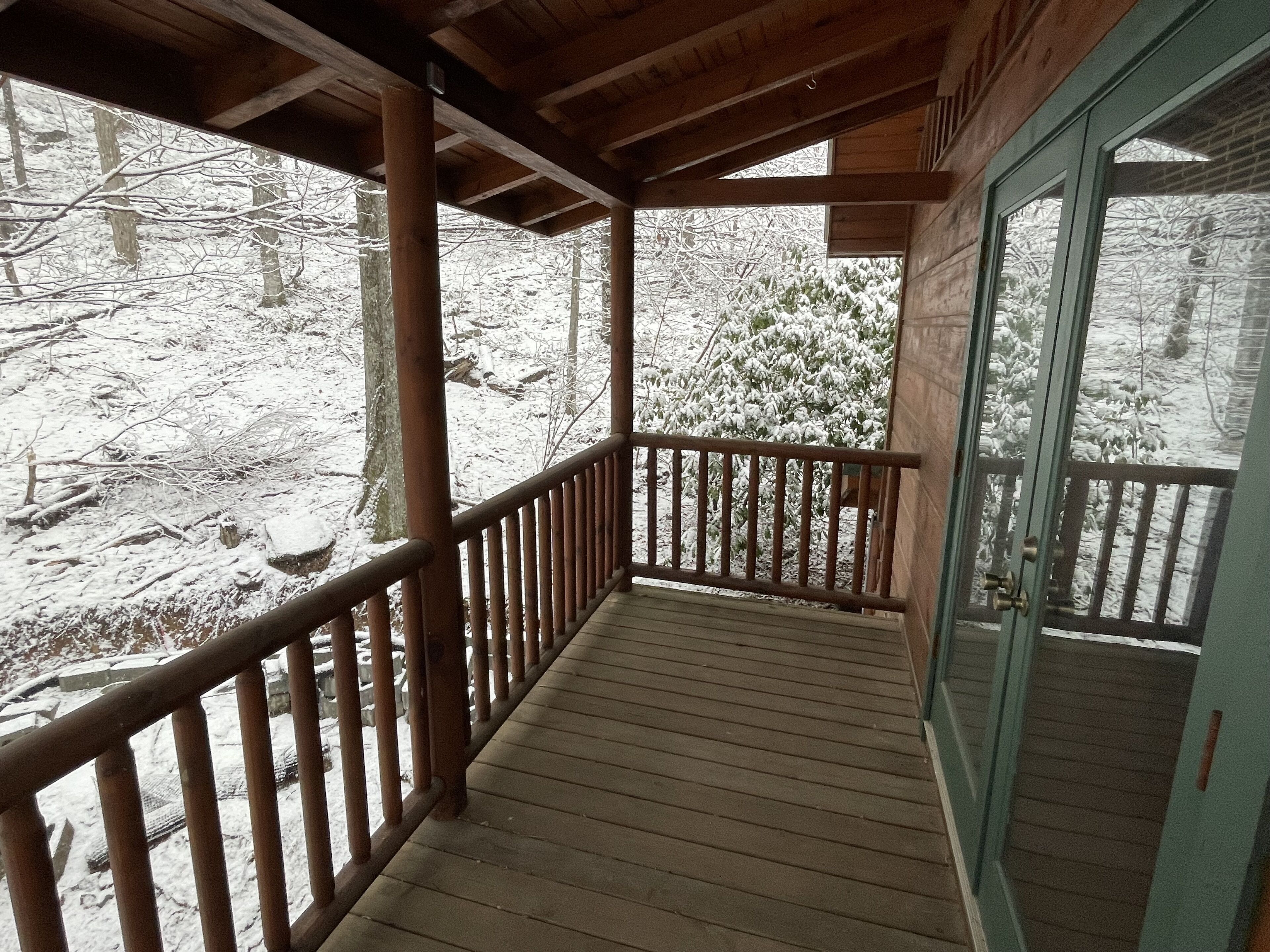 A wooden deck with a railing, leading to a glass door.