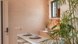 A modern kitchen with a white countertop, two bar stools, a ceiling fan, and potted plants. - Kinal 05 - One Bedroom Apartment, Sleeps 2 (Mérida)