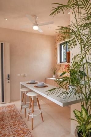 Enjoy dining and socializing in this stylish space with a long table and stools, a potted plant, and a cozy rug.