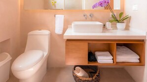 A modern bathroom with a white toilet, a sink with a mirror above, and a small shelf with towels. - Kinal 05 - One Bedroom Apartment, Sleeps 2 (Mérida)