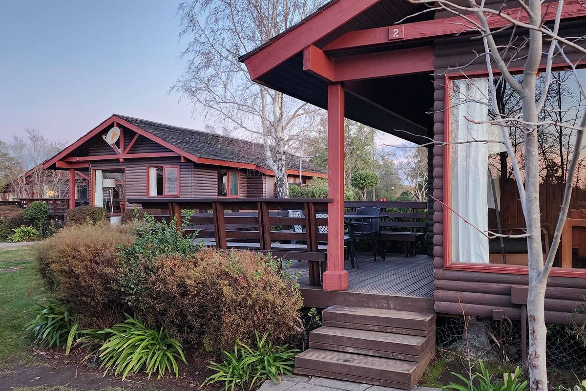 A rustic log cabin with a porch and a small deck.