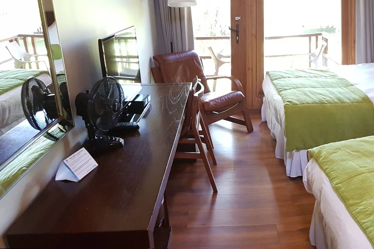 A hotel room with two beds, a wooden desk with a computer, and a chair.