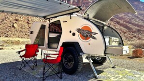 En campingvogn med åben trailer, en rød klapstol og et stengul landskab i baggrunden.