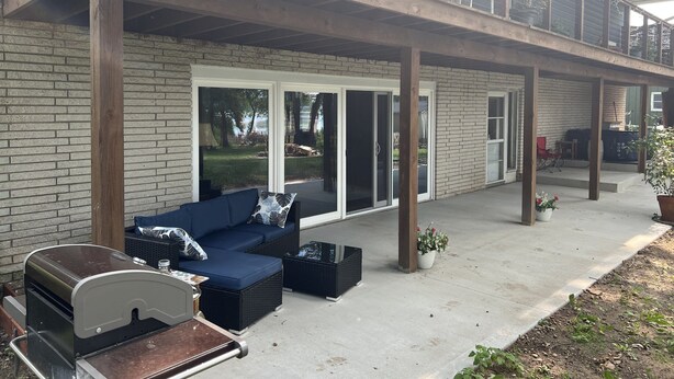 A covered outdoor patio with a built-in grill, seating area, and a view of the backyard.