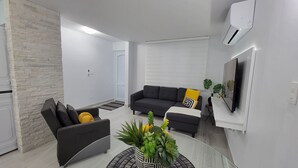 Ein modernes Wohnzimmer mit einer Couch, einem Sessel und einem Couchtisch mit Pflanze.