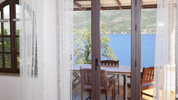 Un balcon avec une table et des chaises, une vue sur la mer et une montagne en arrière-plan.